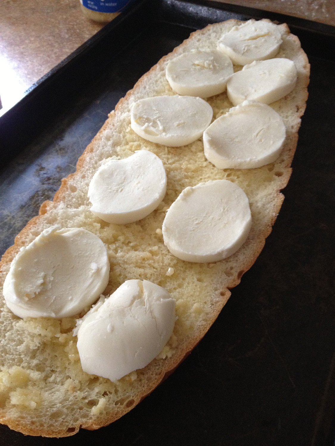 The garlic bread topped with fresh cheese prior to baking.