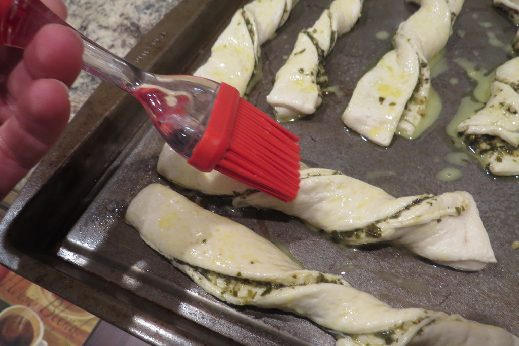 Step 6: Twist the slices, place them onto a greased baking sheet, and brush with an egg wash.